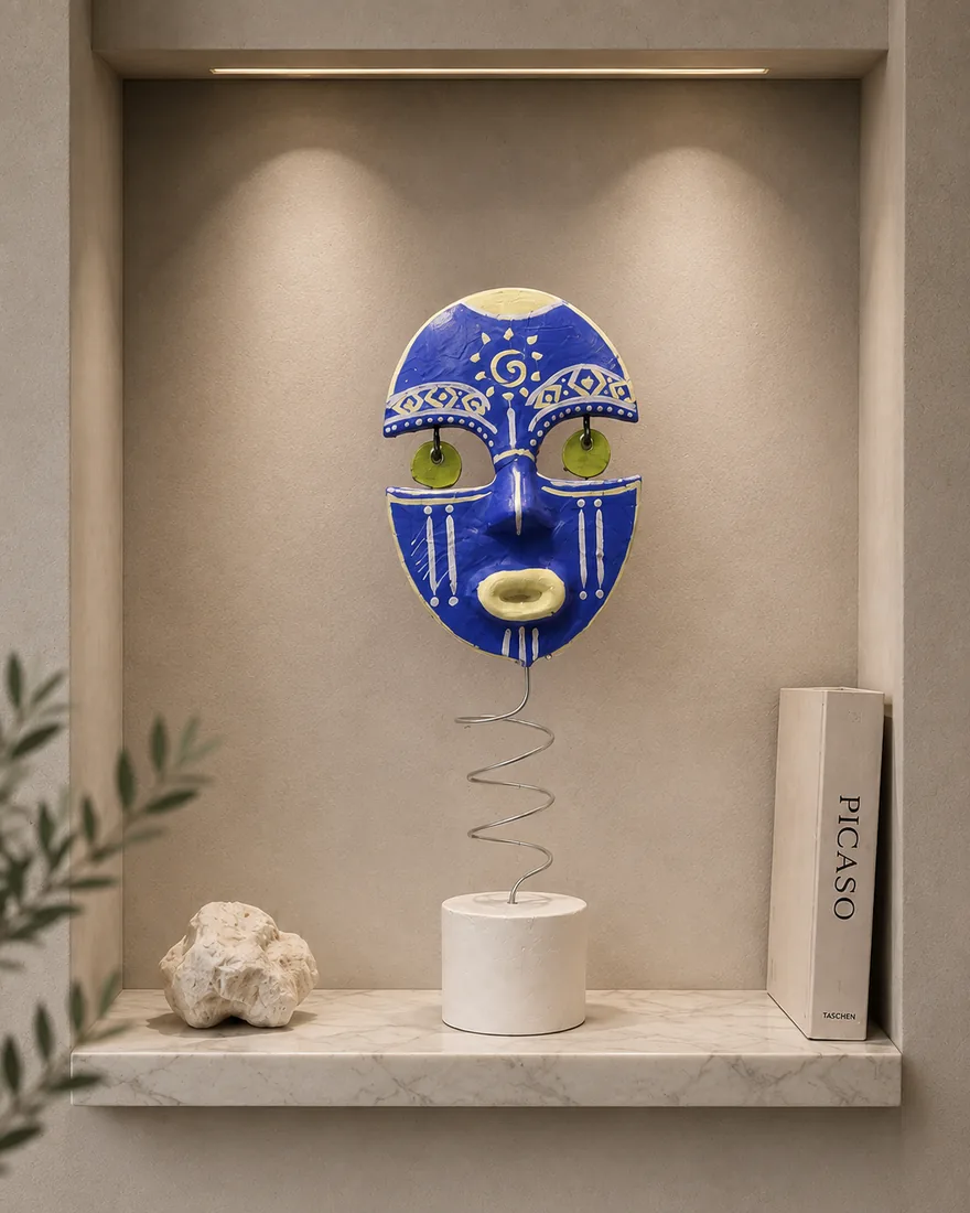 Un masque bleu outremer aux motifs blancs et dorés, boucles vertes, porté par une tige en spirale.